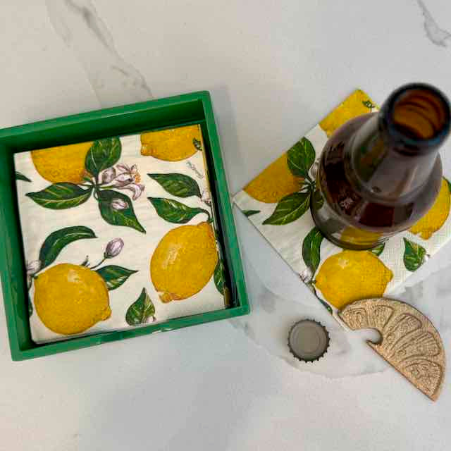 Napkin with lemon design in a green frame on a white marble surface.