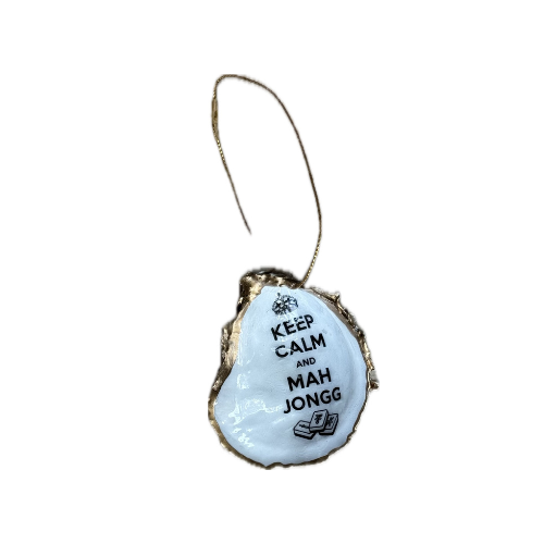 A decorative oyster shell ornament with a gold wire hanger, featuring a white center printed with the text 'KEEP CALM AND MAH JONGG' in black lettering.