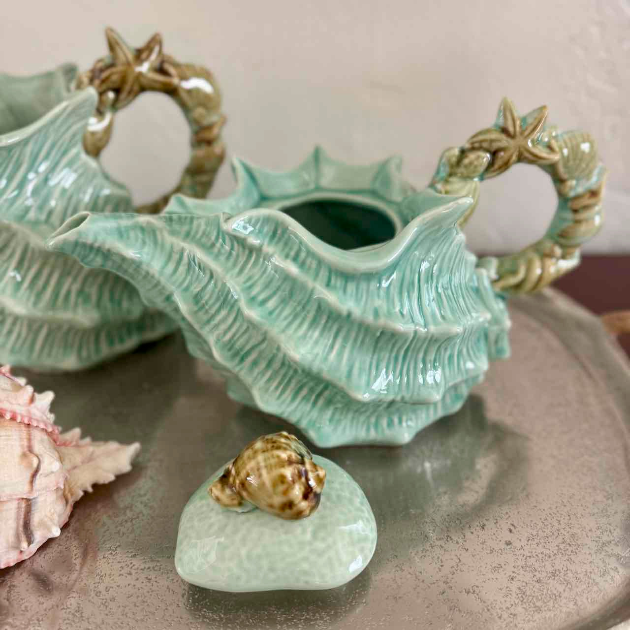 Ceramic shell-shaped vase with starfish handles on a neutral background