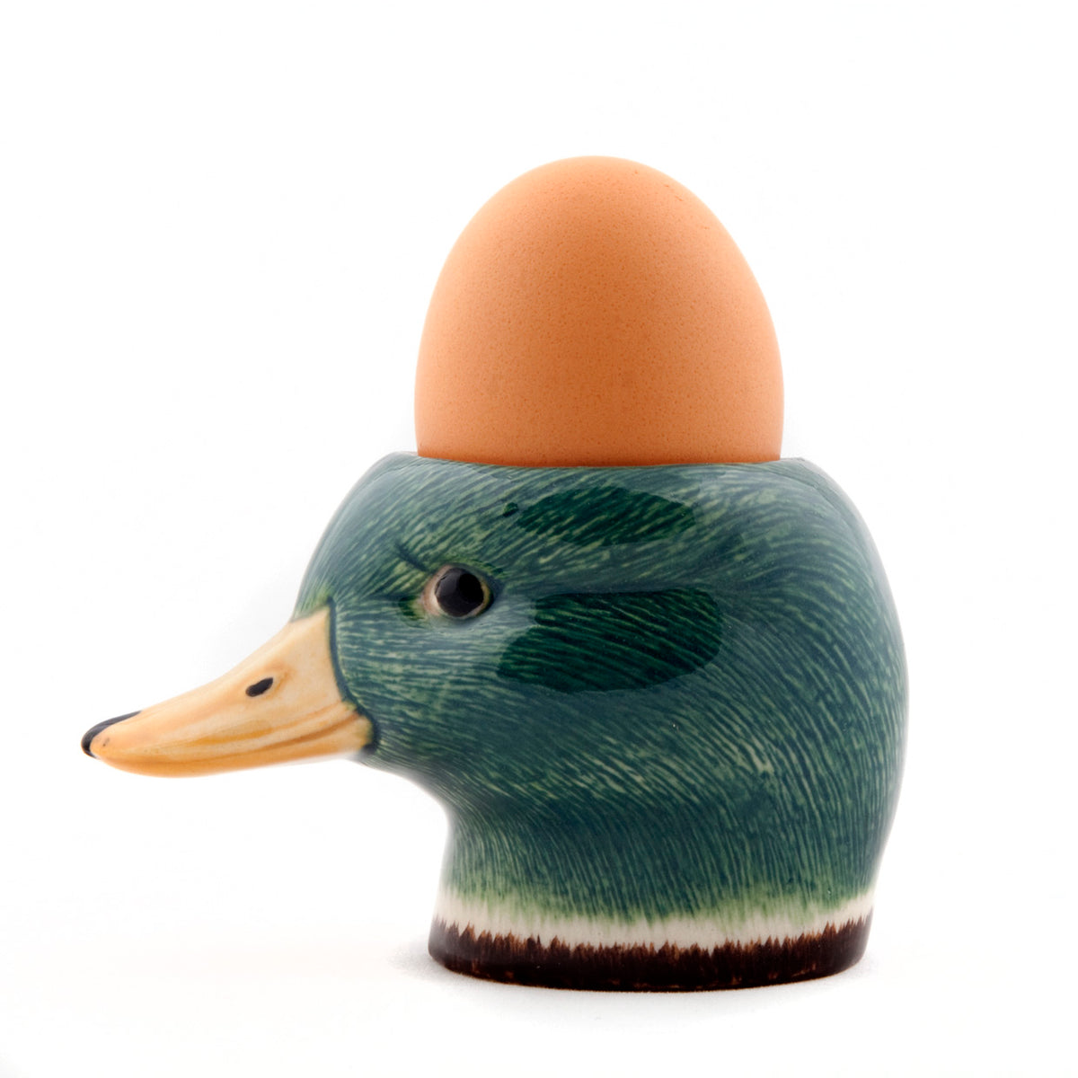 A hand-painted stoneware egg cup shaped like a duck with a brown egg placed on top.