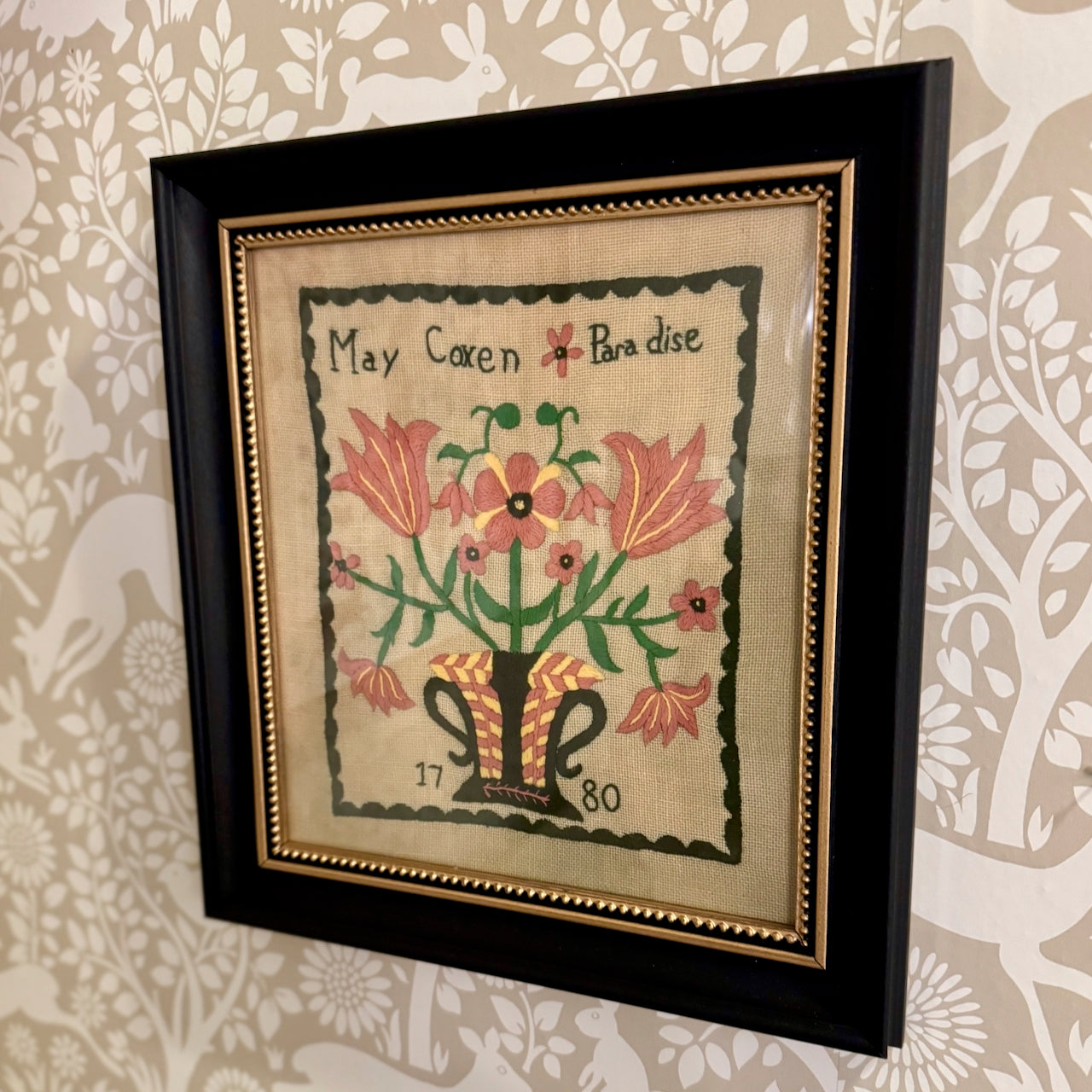 Framed artwork with floral design and text on a patterned wall