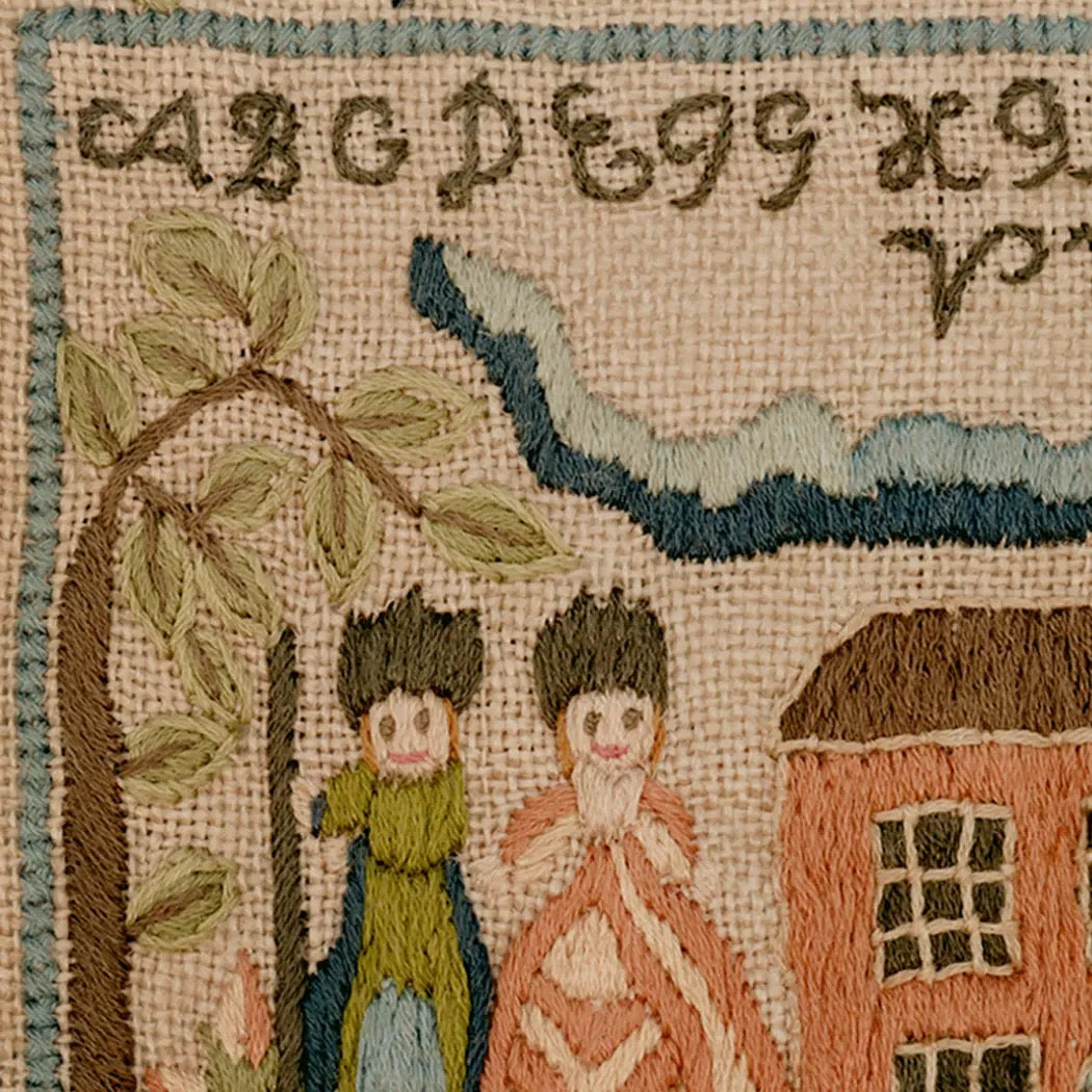 Embroidered scene with two figures, a house, and text on a textured fabric background.