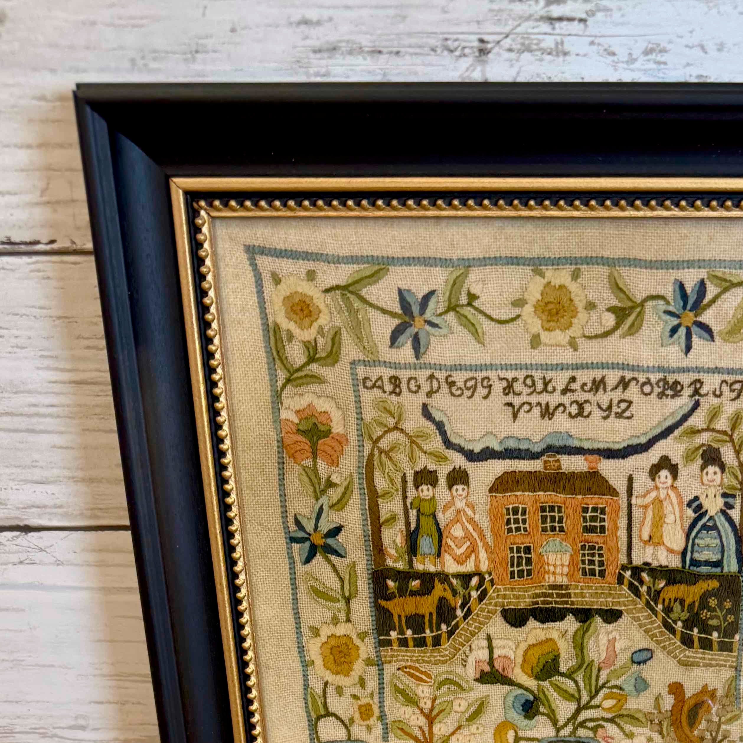 Framed needlepoint with decorative elements on a wooden surface