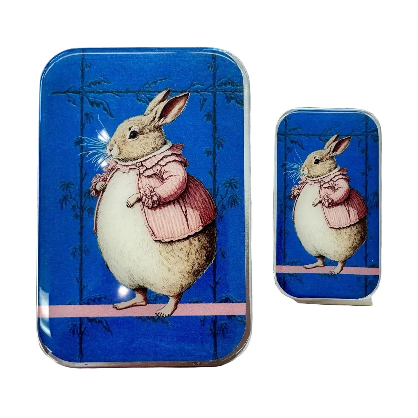 Two tin boxes with a rabbit illustration on a wooden surface with lavender flowers.