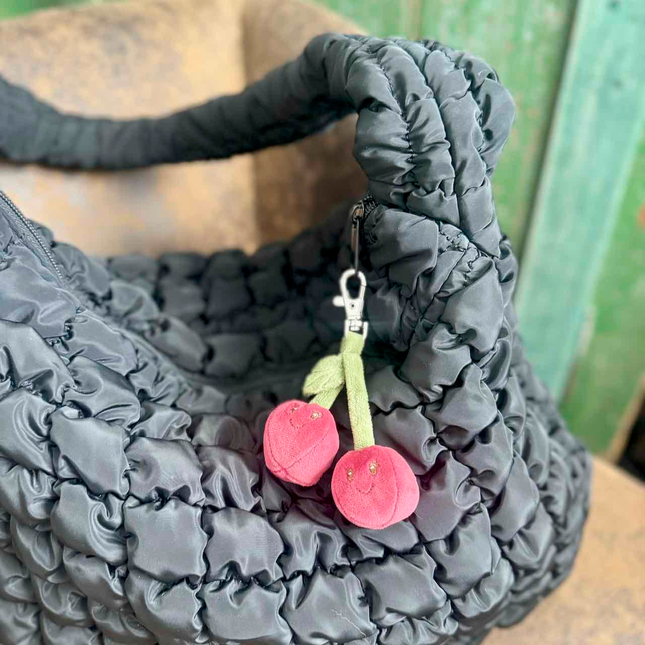 Gray textured bag with a cherry-shaped keychain attached