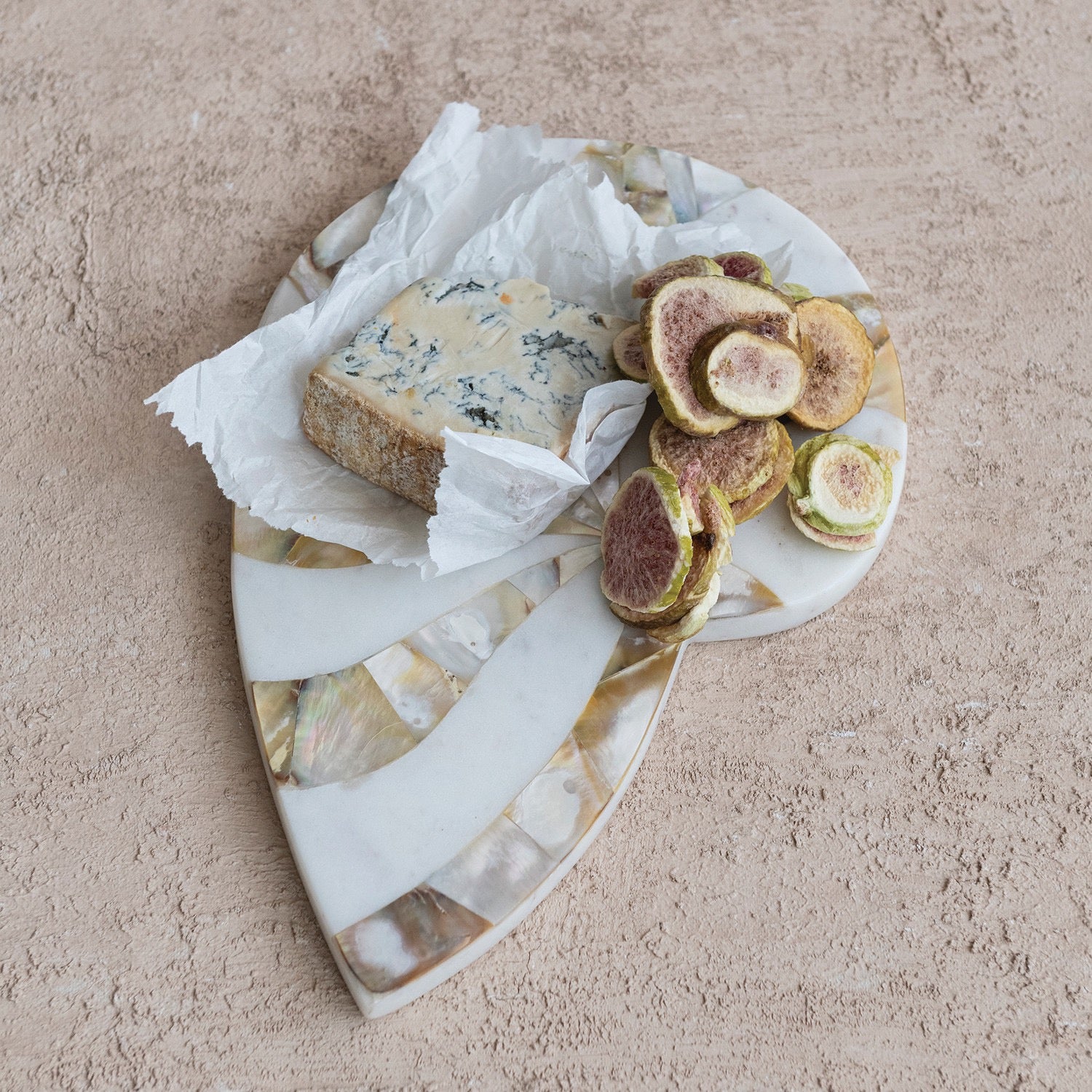 Marble cheese board with blue cheese and sliced figs on a beige surface