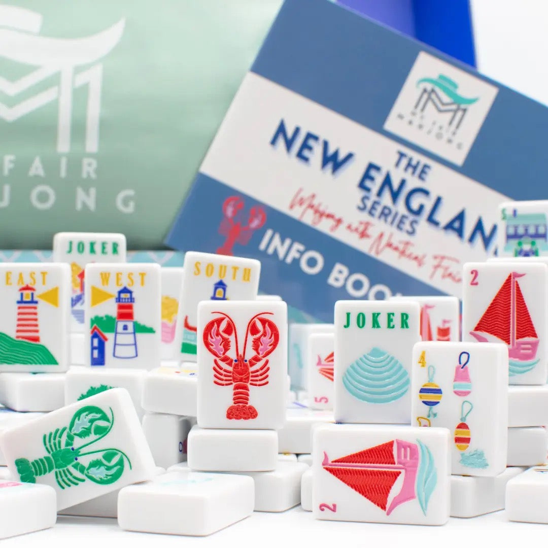 Set of colorful game tiles with a 'New England' theme and an info book in the background.