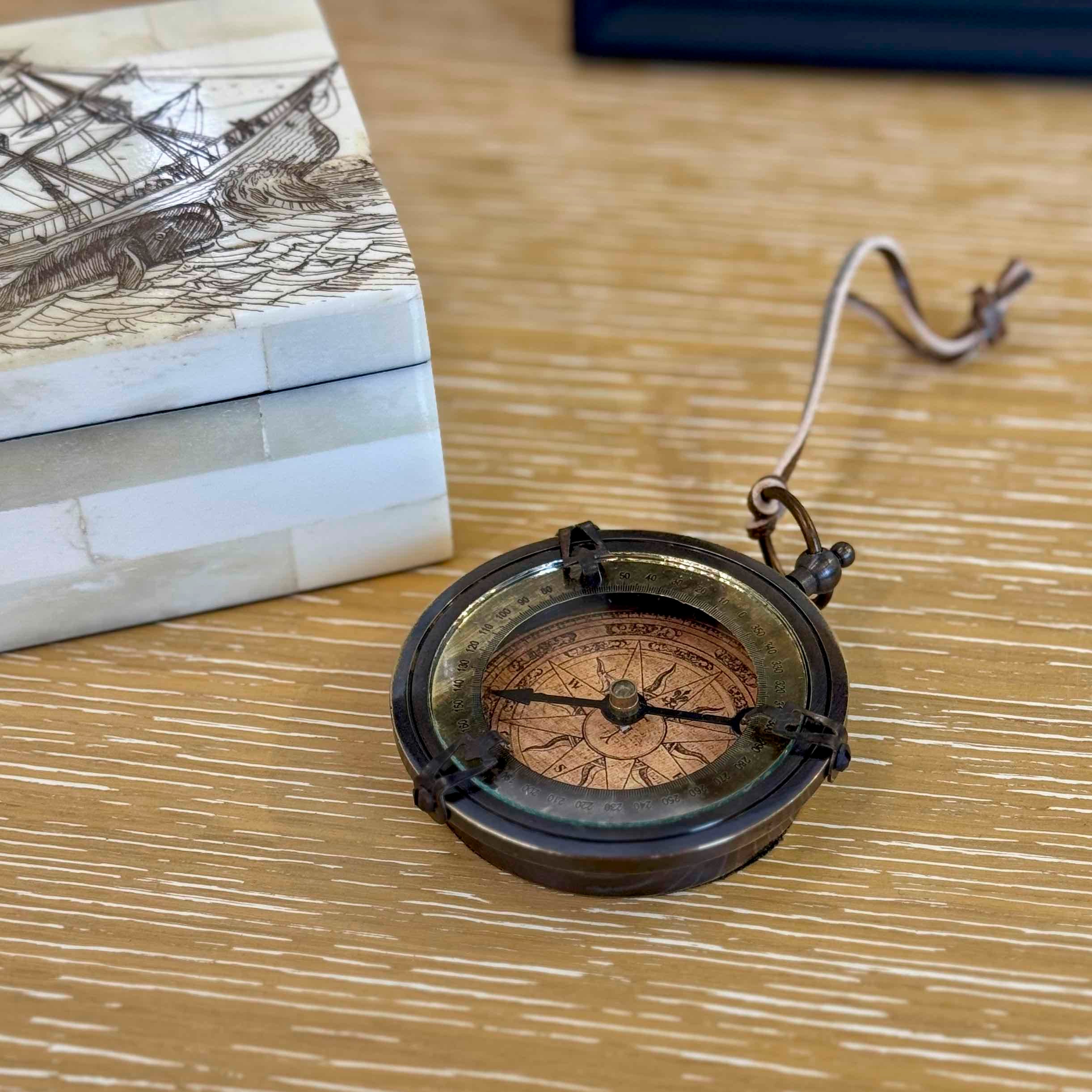 Vintage-style compass on a wooden surface with books in the background