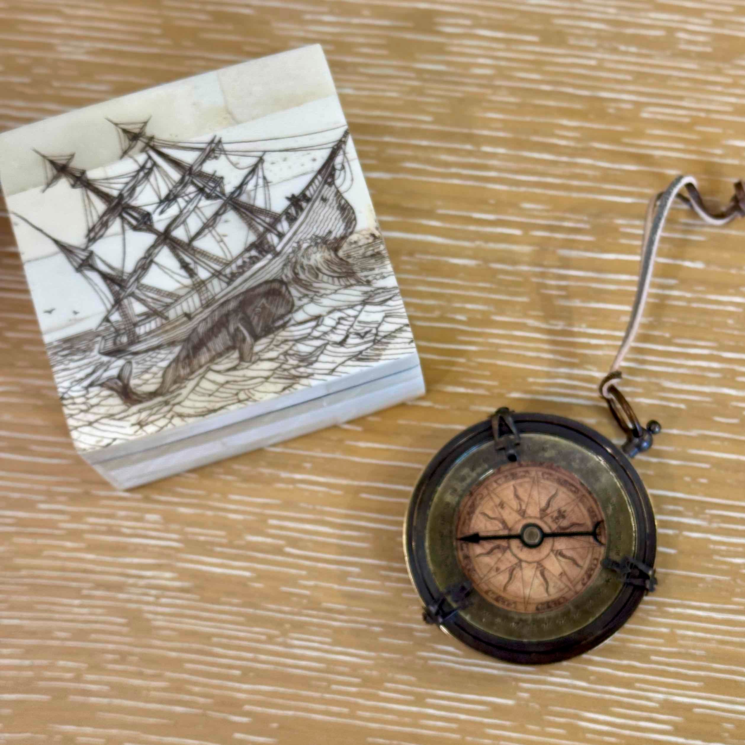 Vintage-style compass and ship illustration on a wooden surface