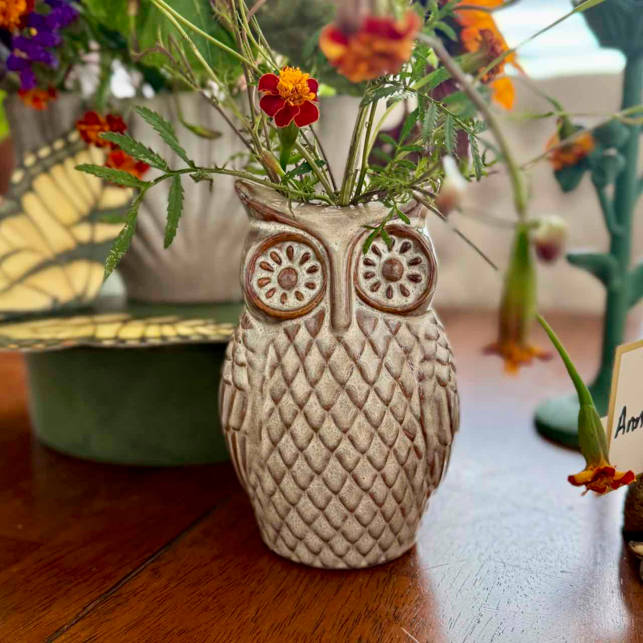 Ceramic owl vase with flowers on a wooden surface