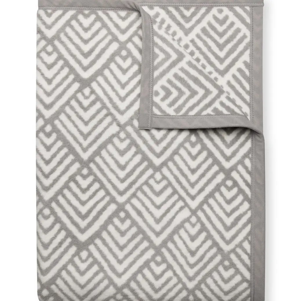 Gray and white geometric patterned blanket on a white background