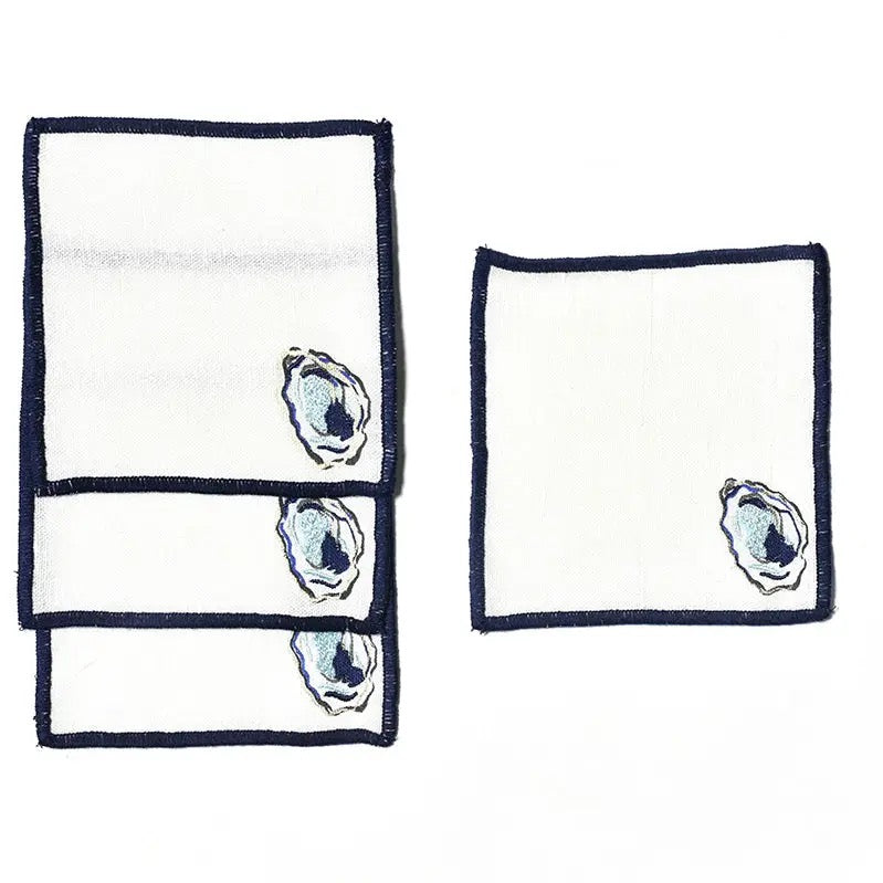 Two white napkins with blue oyster shell designs on a white background