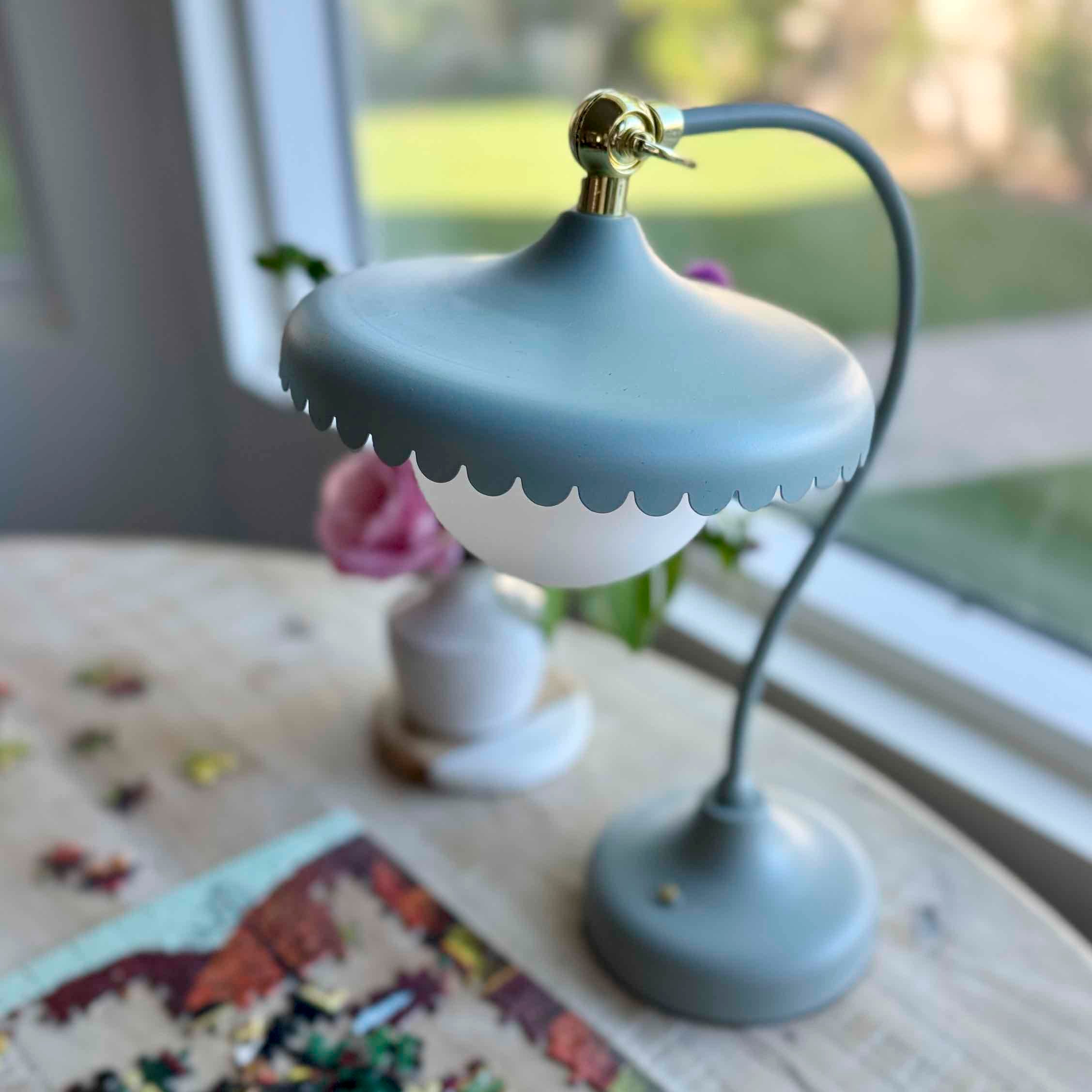 Small blue lamp on a surface with a window in the background