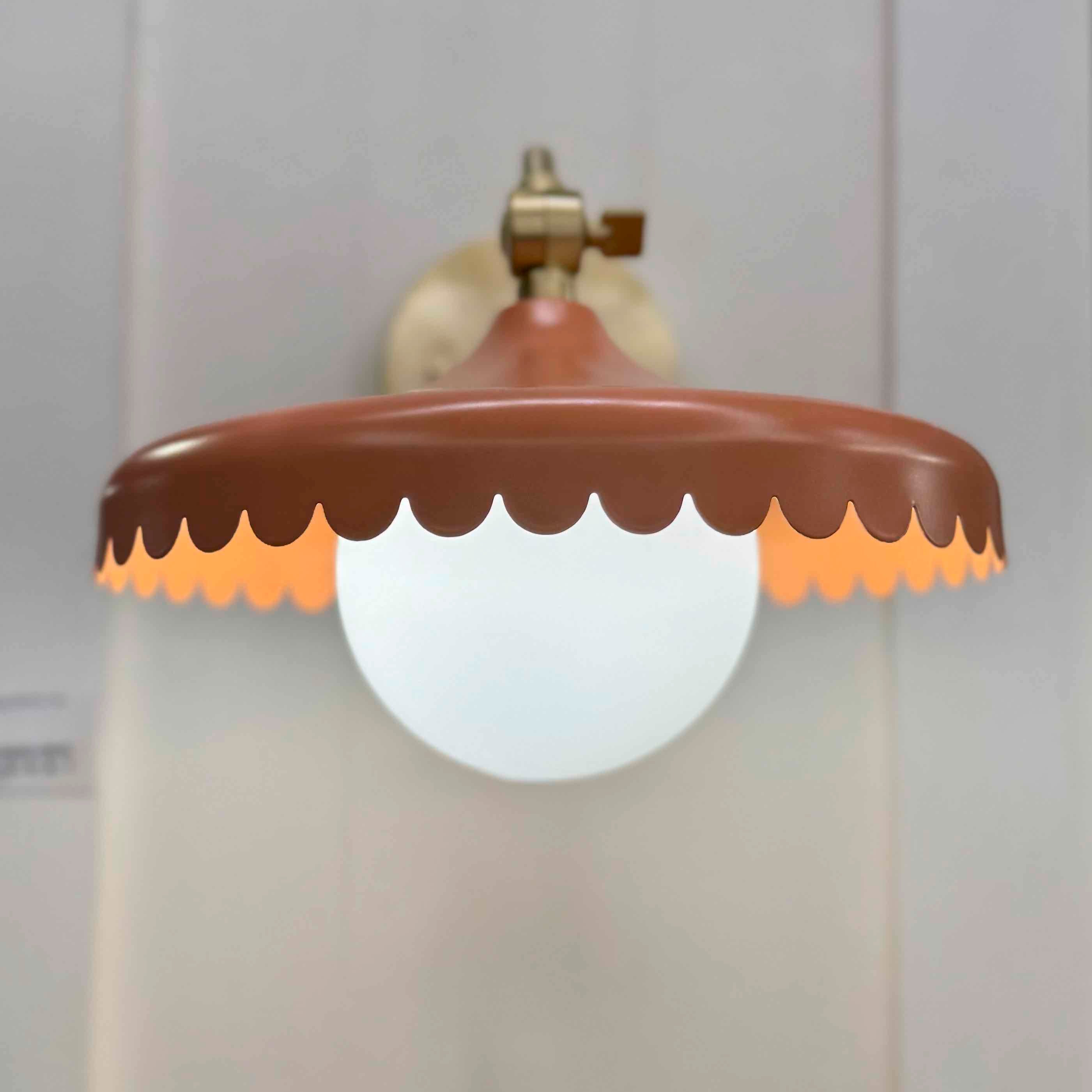Decorative wall light fixture with scalloped brown shade on a plain background