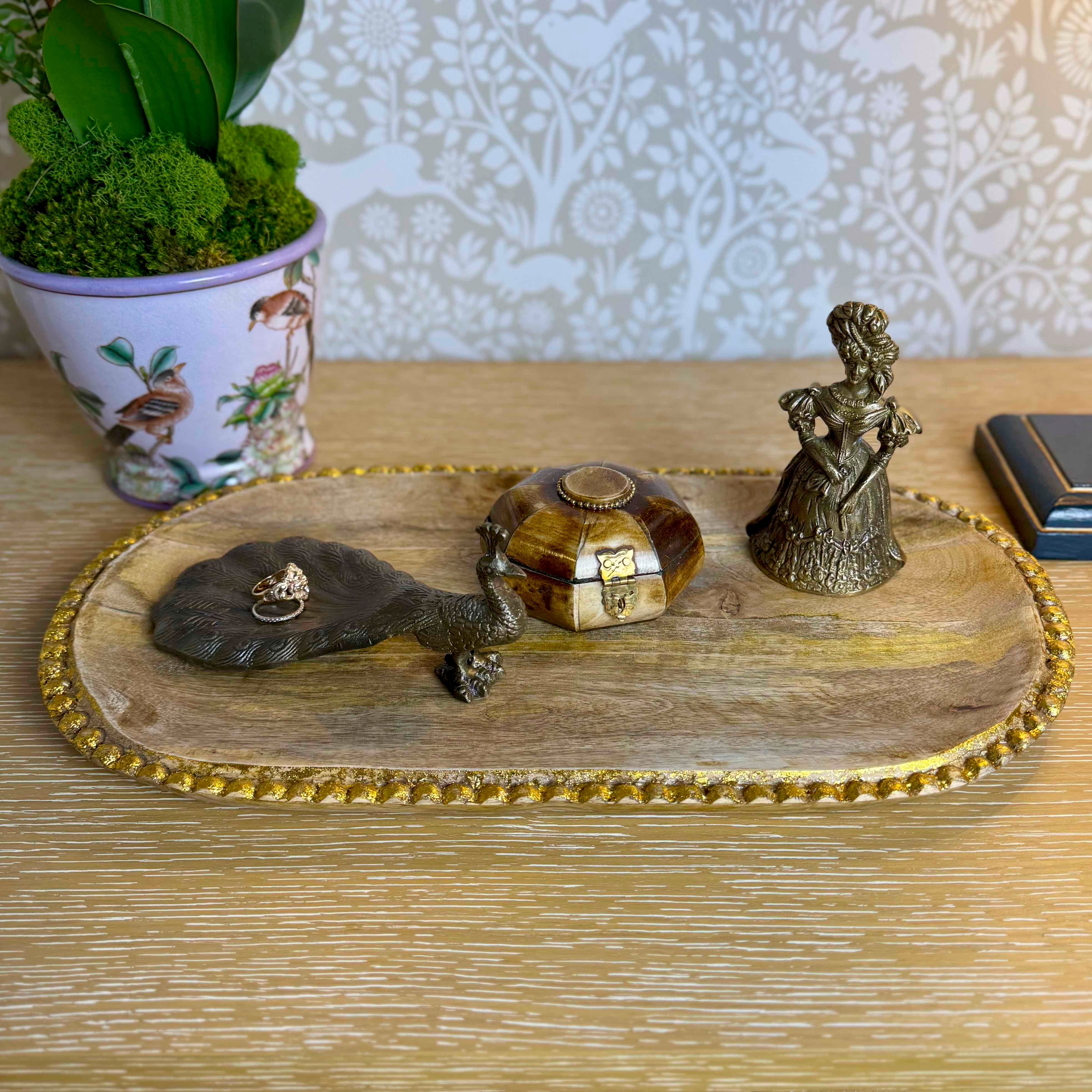 Decorative items on a wooden tray with a plant in the background