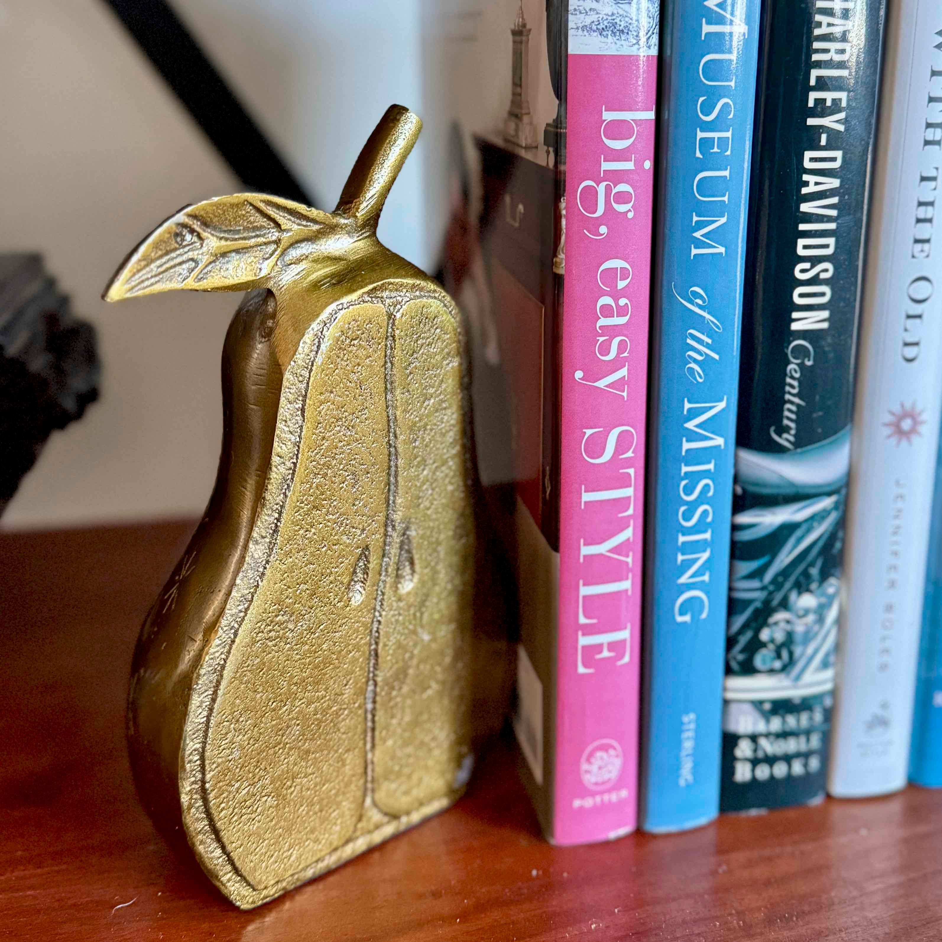 Gold pear-shaped object next to a row of books on a wooden surface