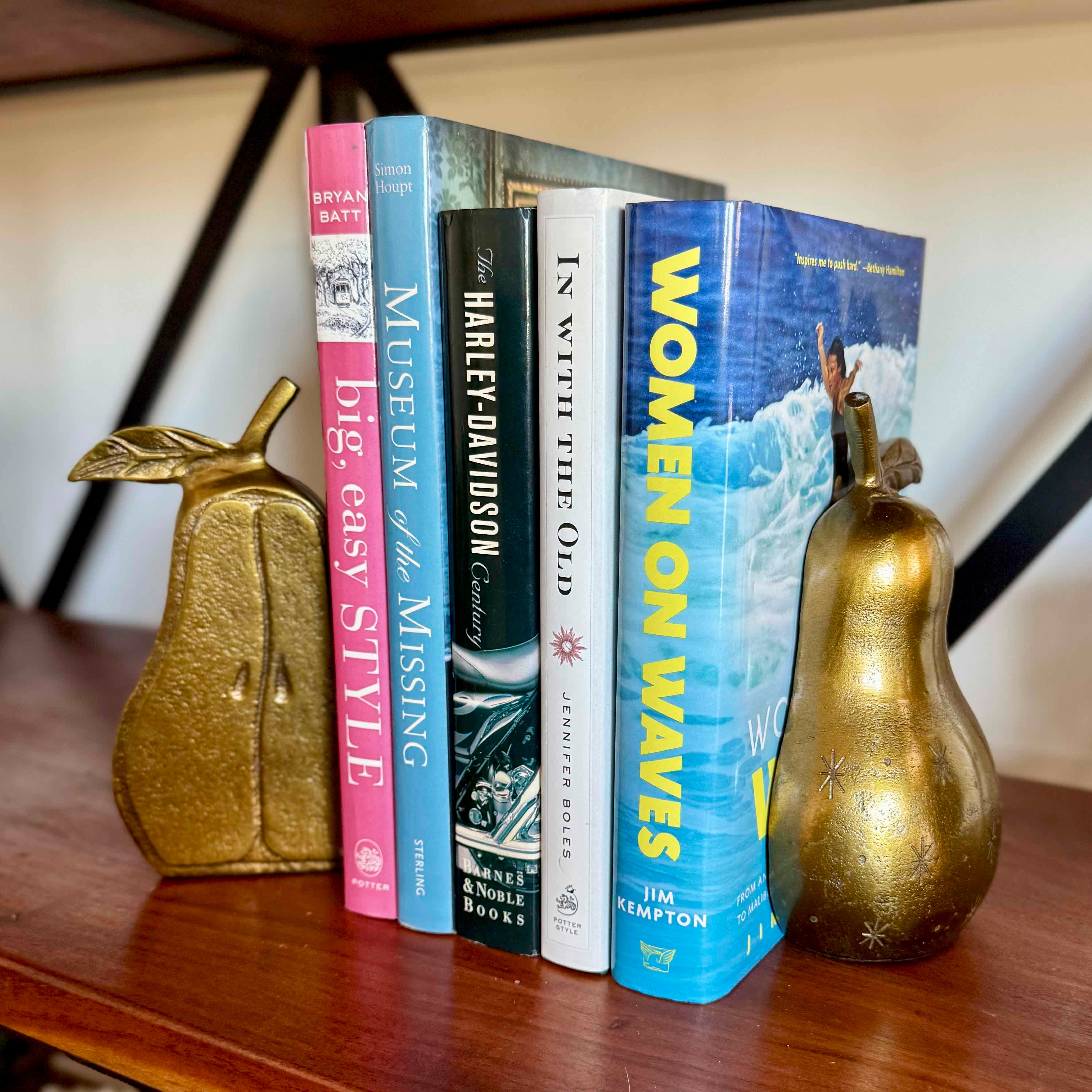Stack of books on a wooden surface with decorative pear-shaped objects.