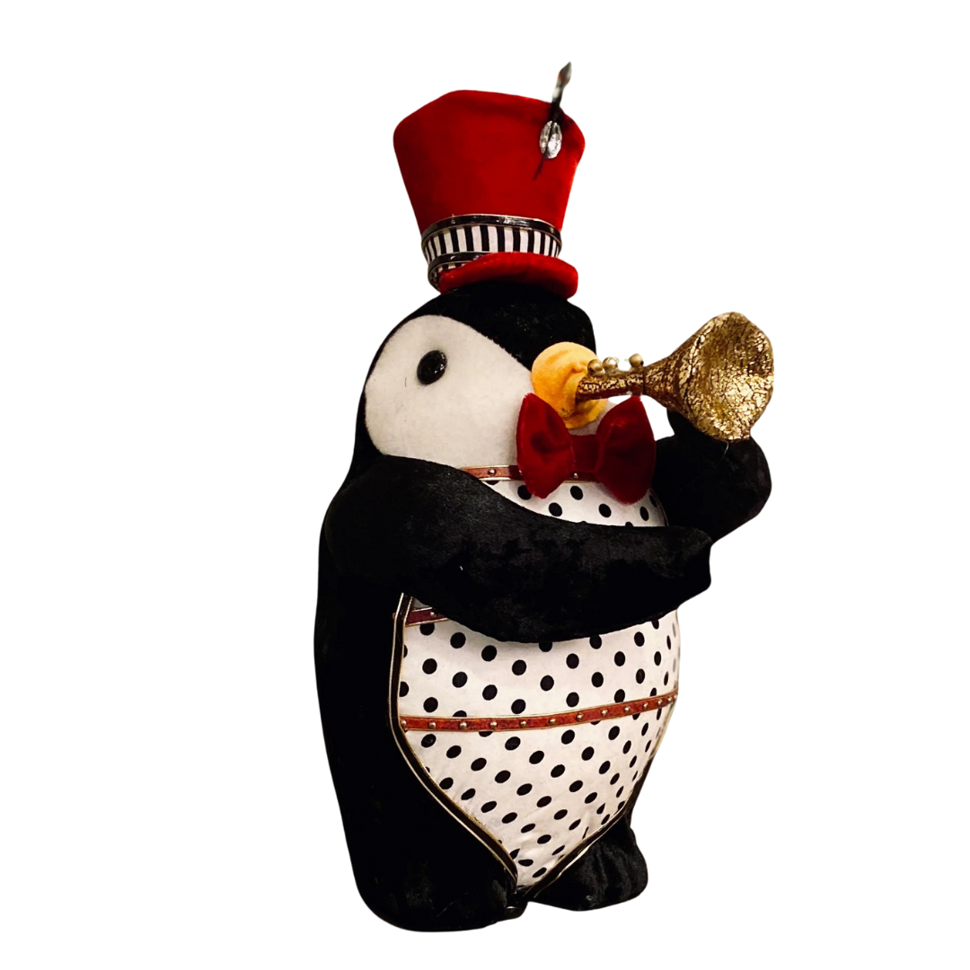 Decorative penguin figurine wearing a red hat and holding a gold trumpet on a white background