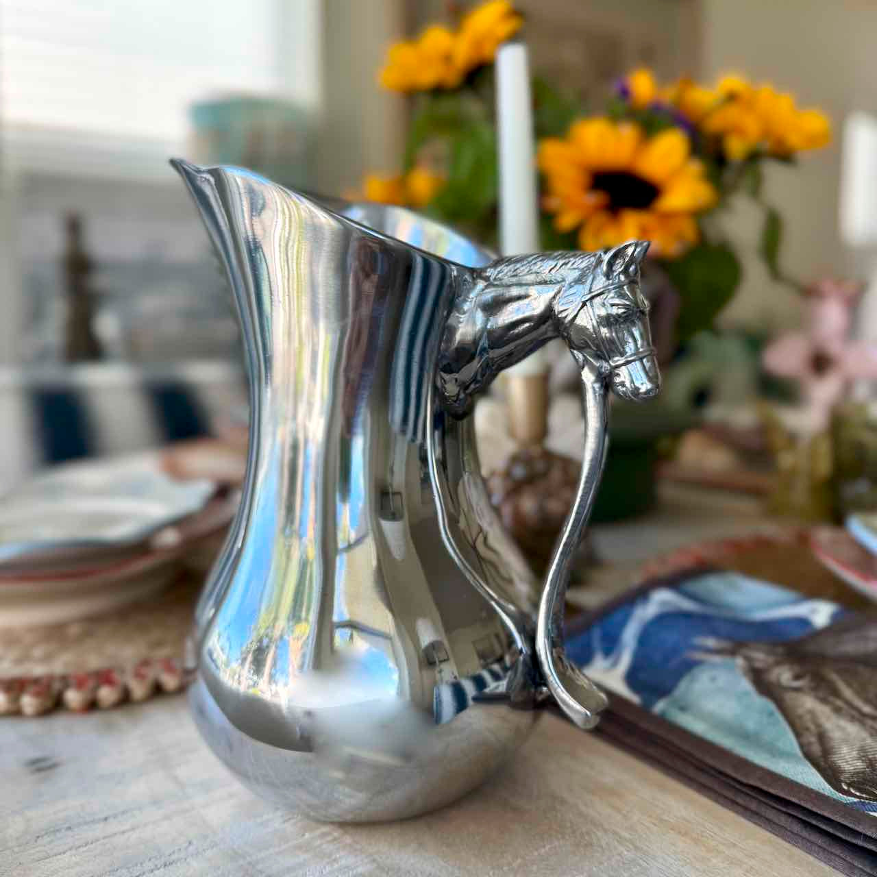 Silver horse-head pitcher on a table with a blurred background