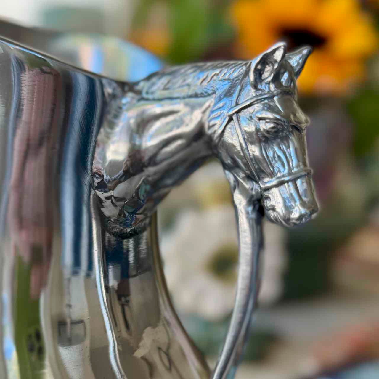 Metallic horse head emblem on a blurred natural background