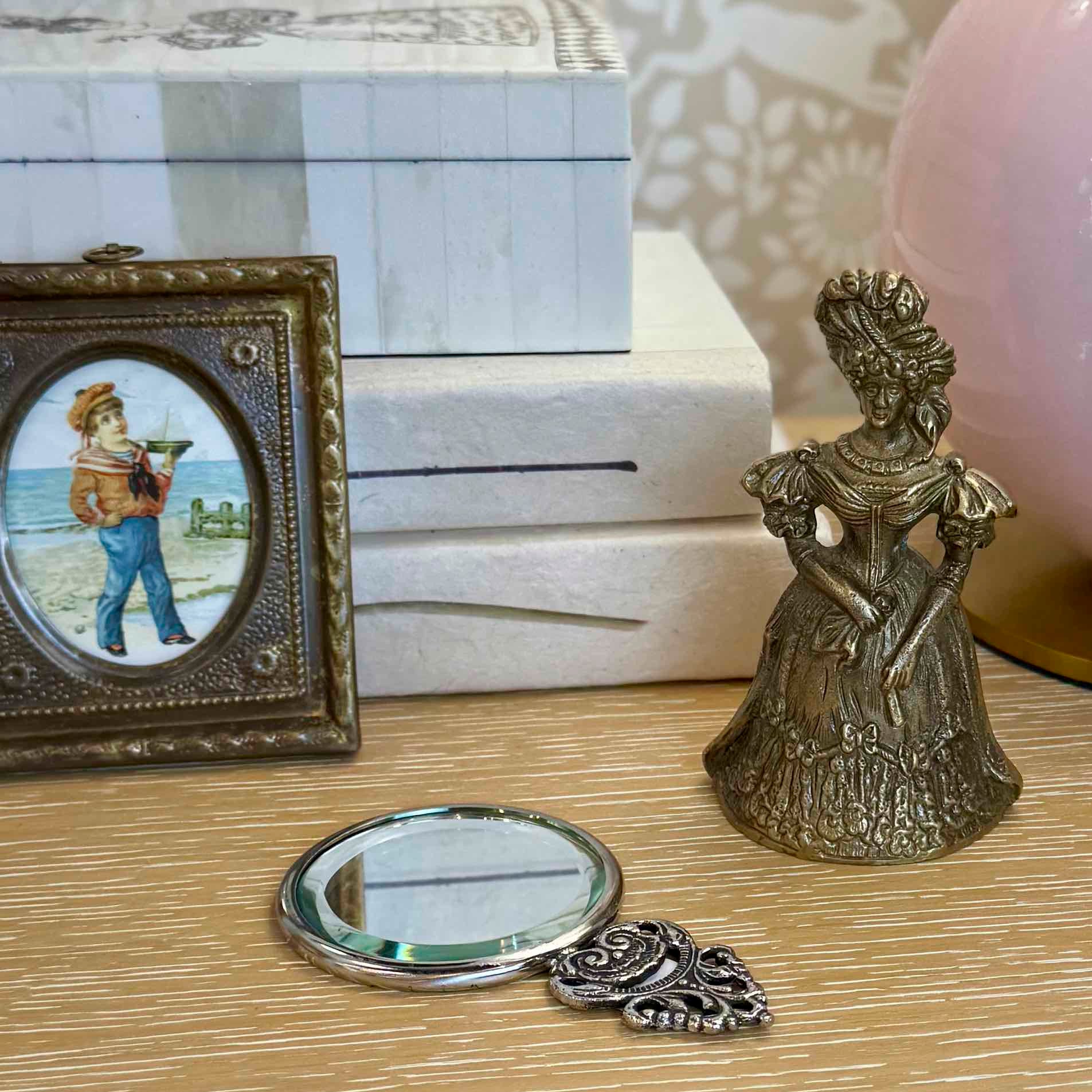 Decorative items including a small round mirror, a figurine, and a framed picture on a surface.