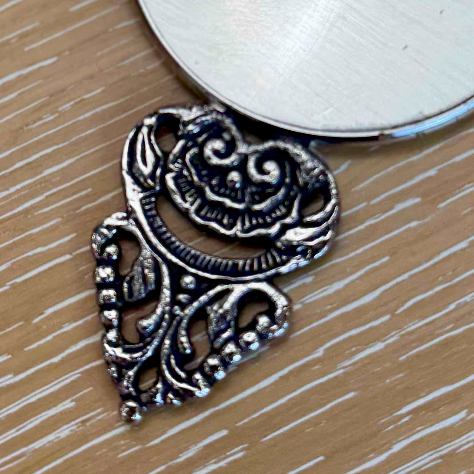 Silver decorative pendant on a wooden surface
