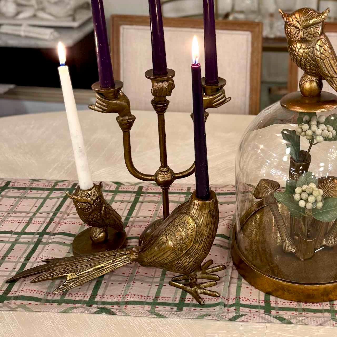 Decorative candle holder with candles and owl-themed items on a table.