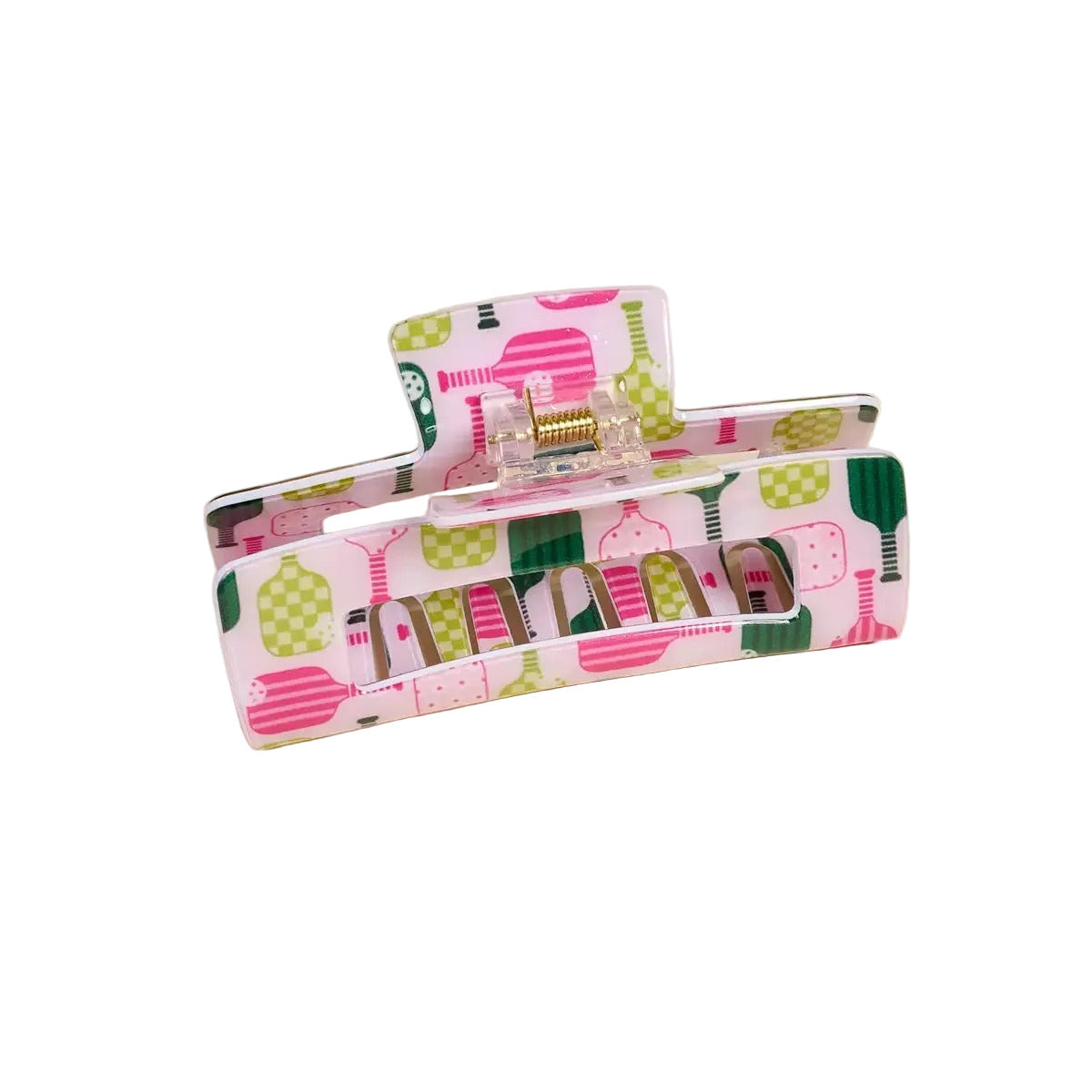 A hair claw clip with a pink, green, and white patterned design, featuring illustrations of cocktail glasses and checkered motifs, shown on a solid beige background.