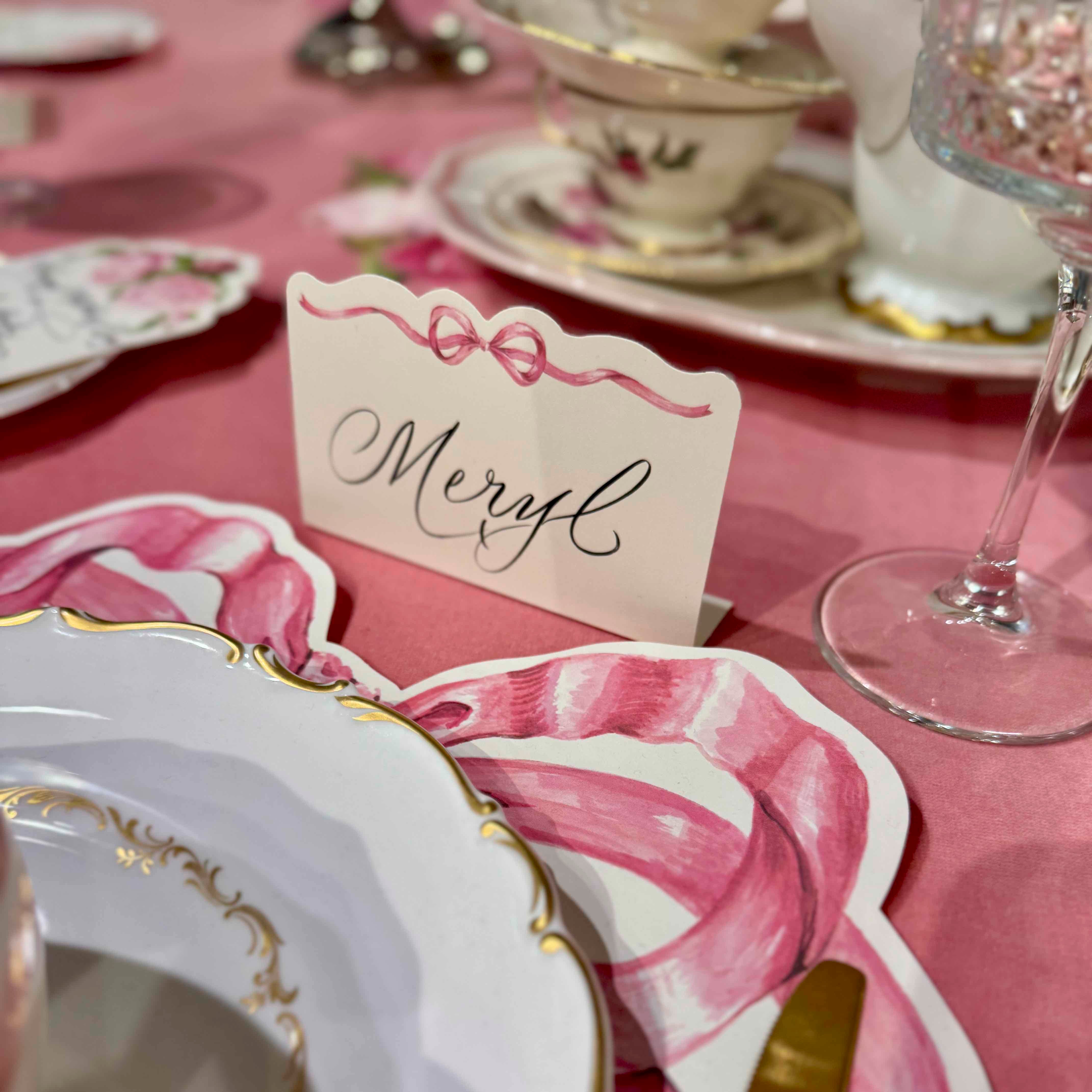 Decorative table setting with a 'Meryl' card on a pink tablecloth.