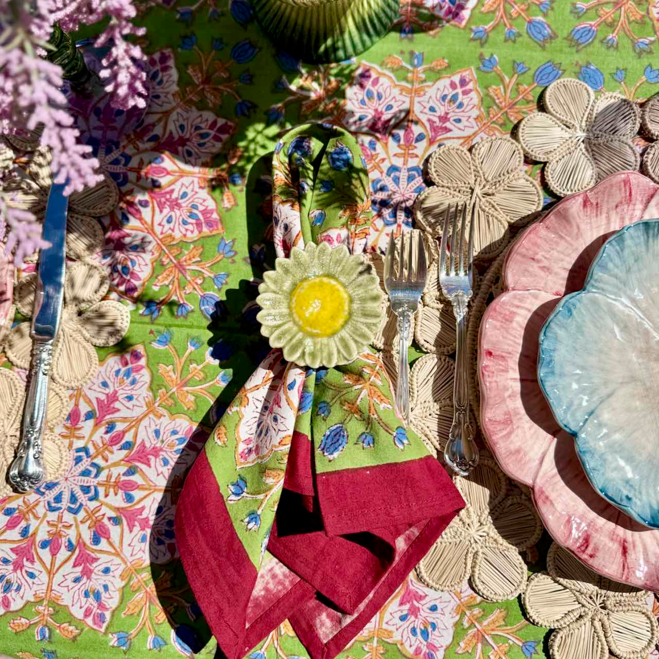 Colorful table setting with floral placemats, plates, and cutlery.