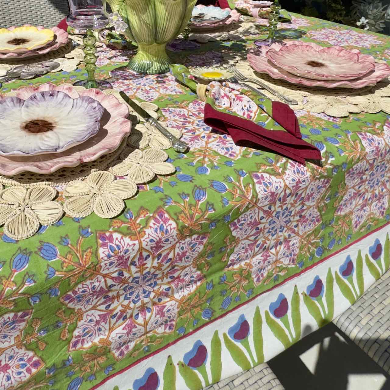 Colorful floral-patterned tablecloth on a table with cutlery and plates.