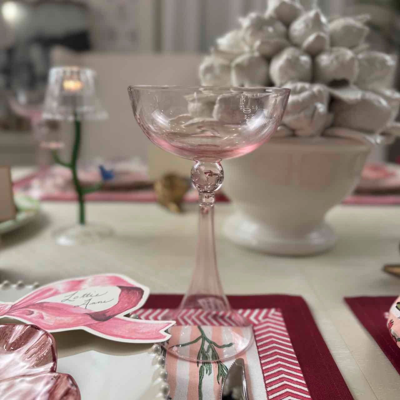 Decorative table setting with a glass, place card, and candle.