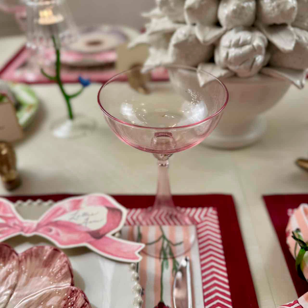 Pink glass on a decorated table with floral arrangements and place settings.