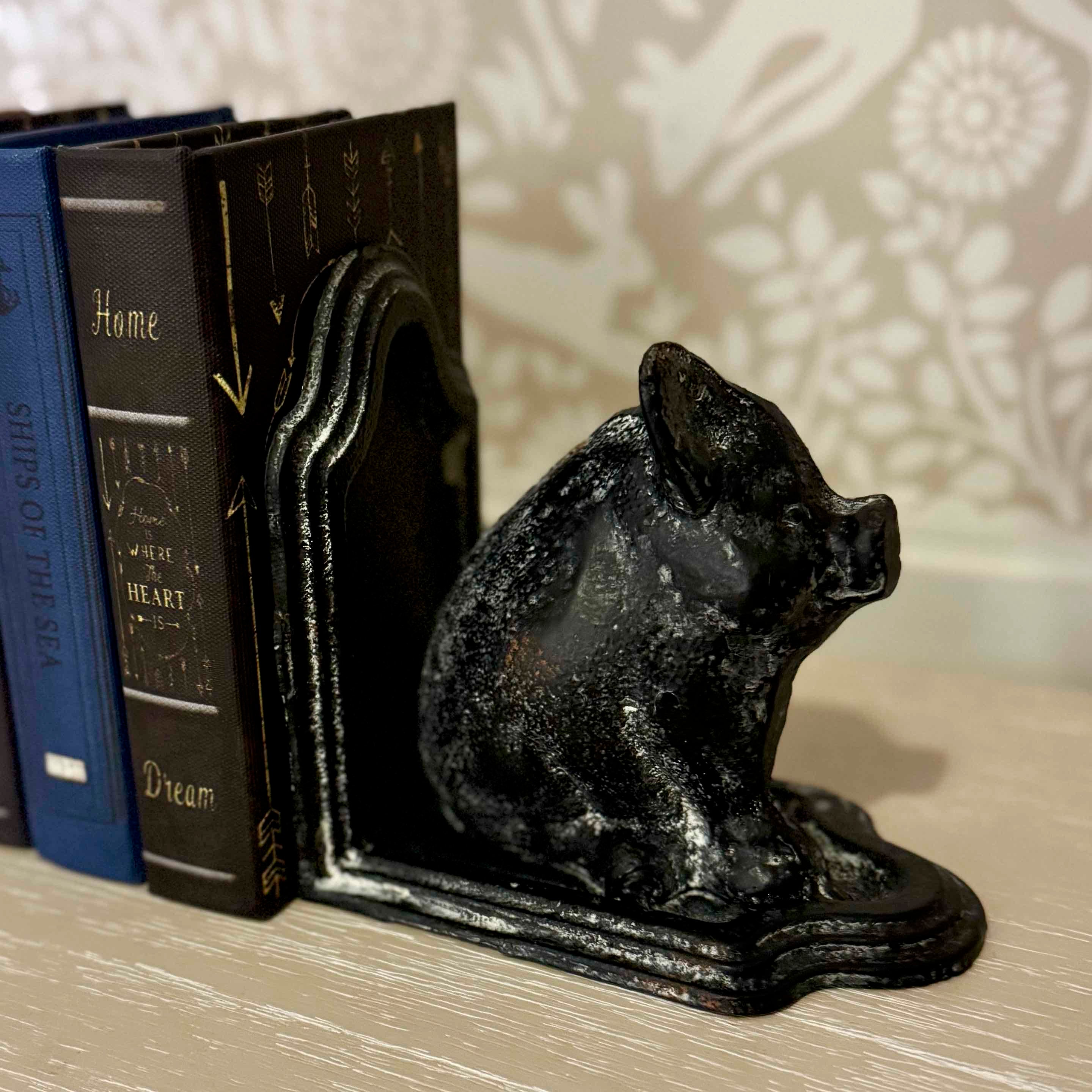 Black cast iron pig-shaped bookend on a surface with books in the background.