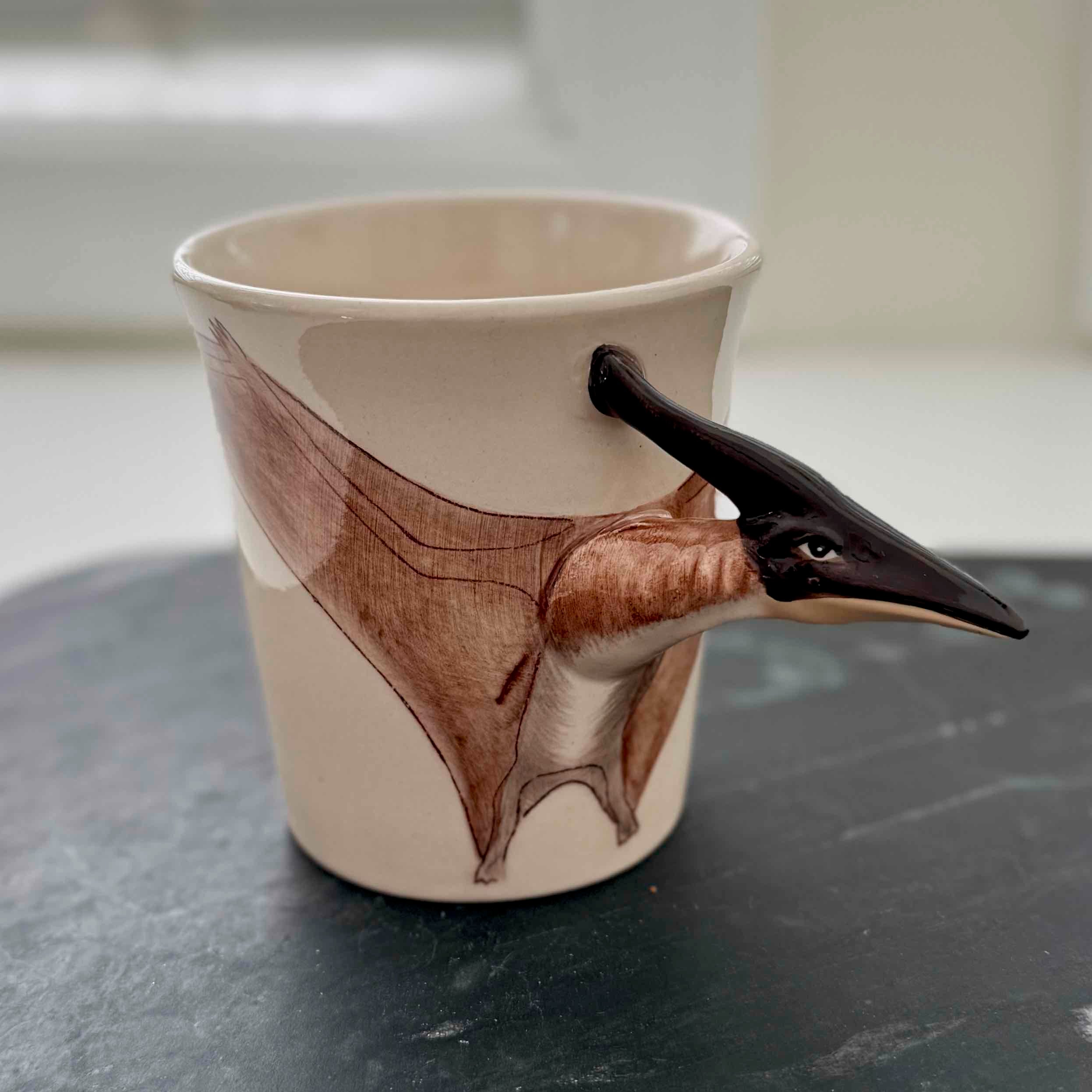Mug with a bird-shaped handle on a dark surface