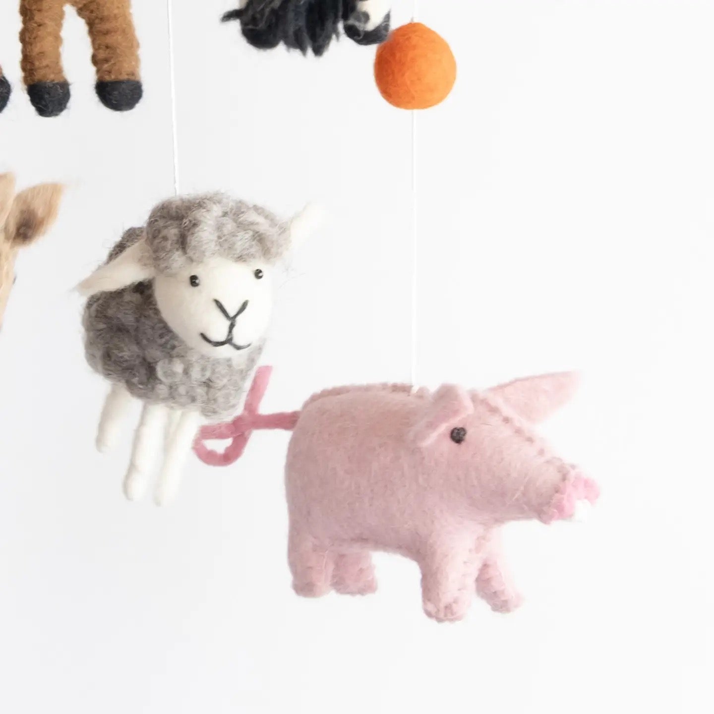 Felted animal toys including a sheep, pig, and a black cat on a white background