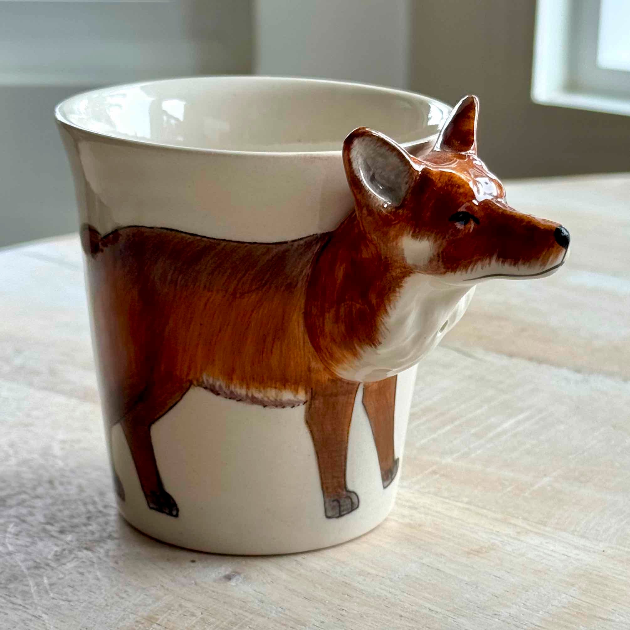 Ceramic mug with a fox design on a wooden surface
