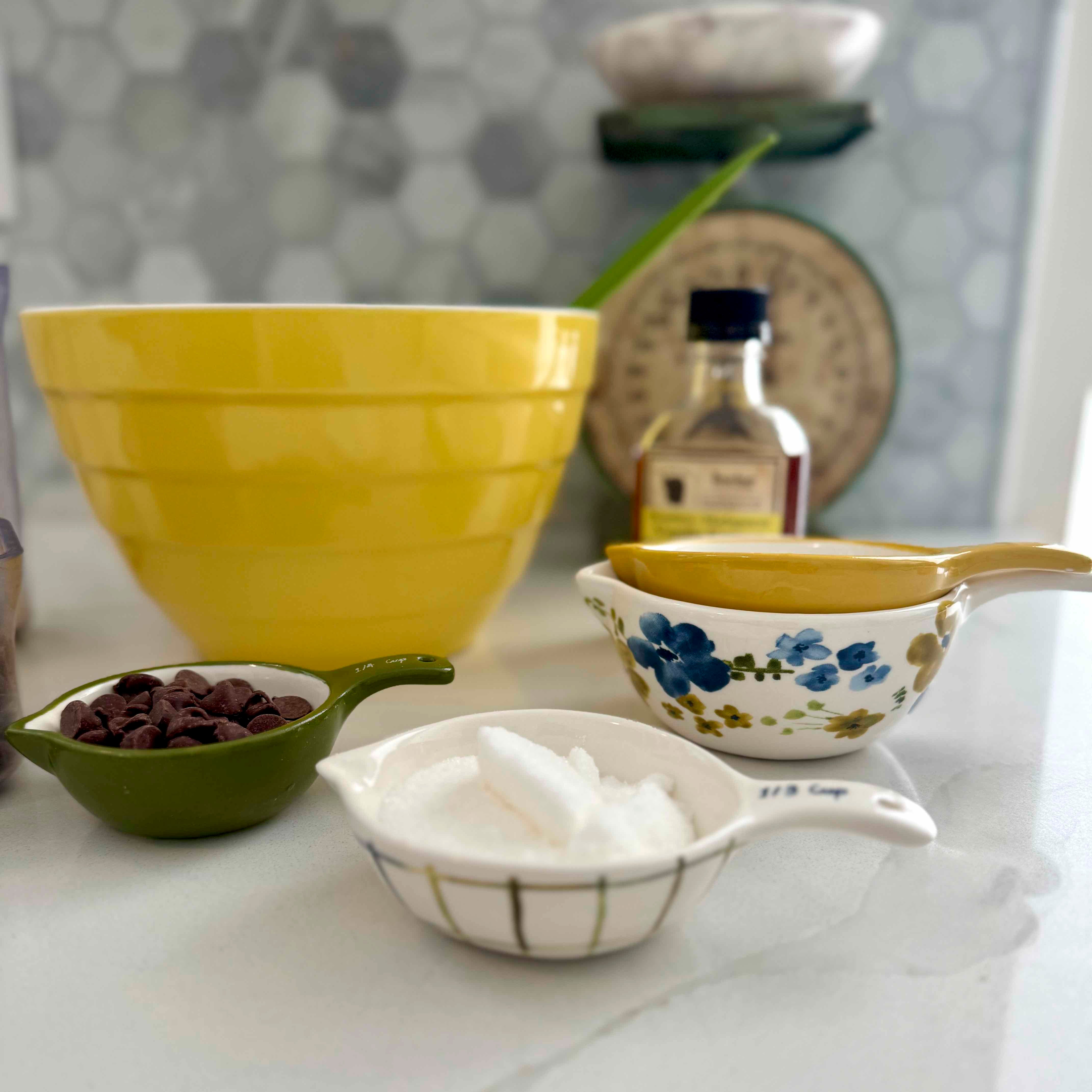 Kitchen counter with various utensils including a yellow bowl, measuring cups, and a bottle of oil.