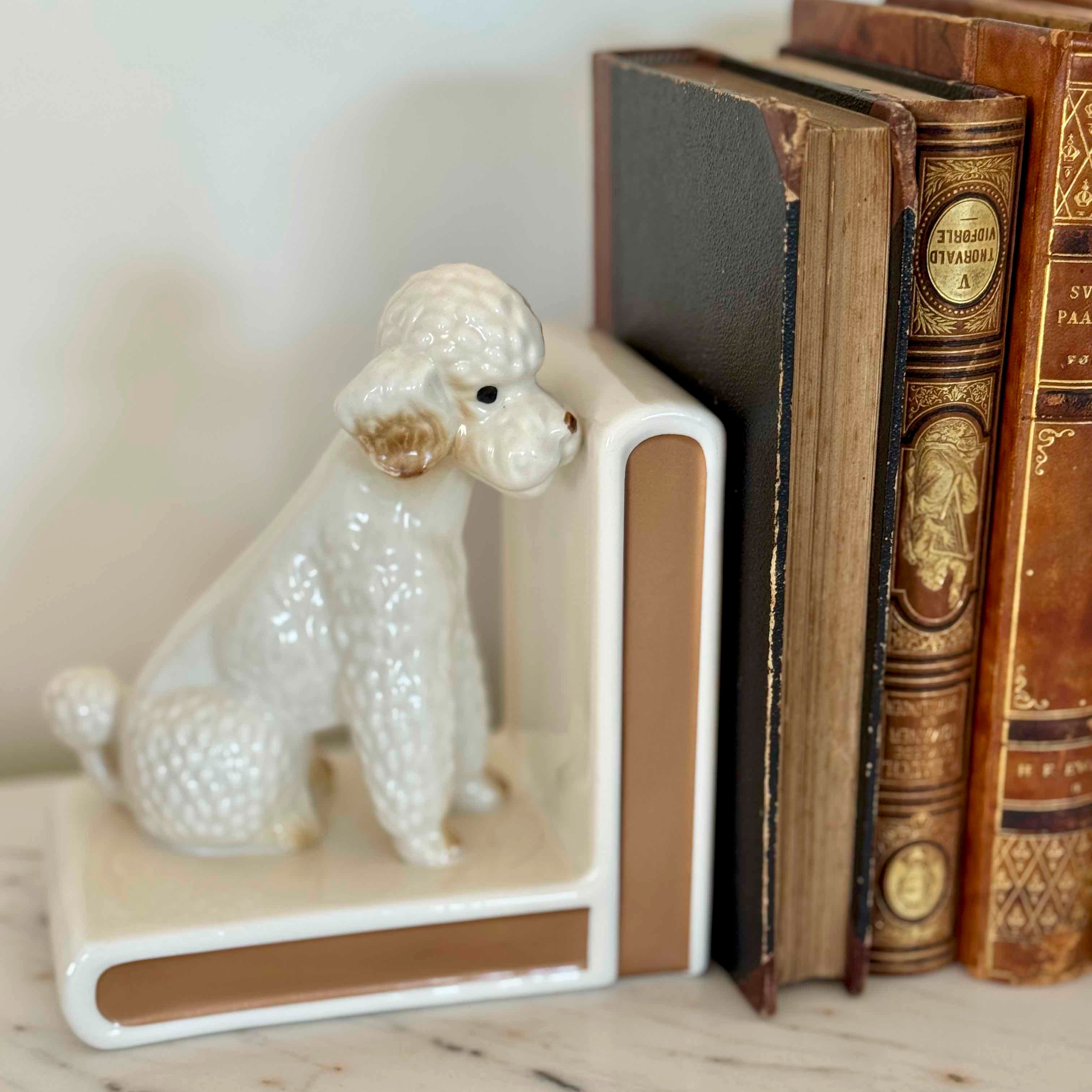 White ceramic dog bookend next to vintage books on a marble surface