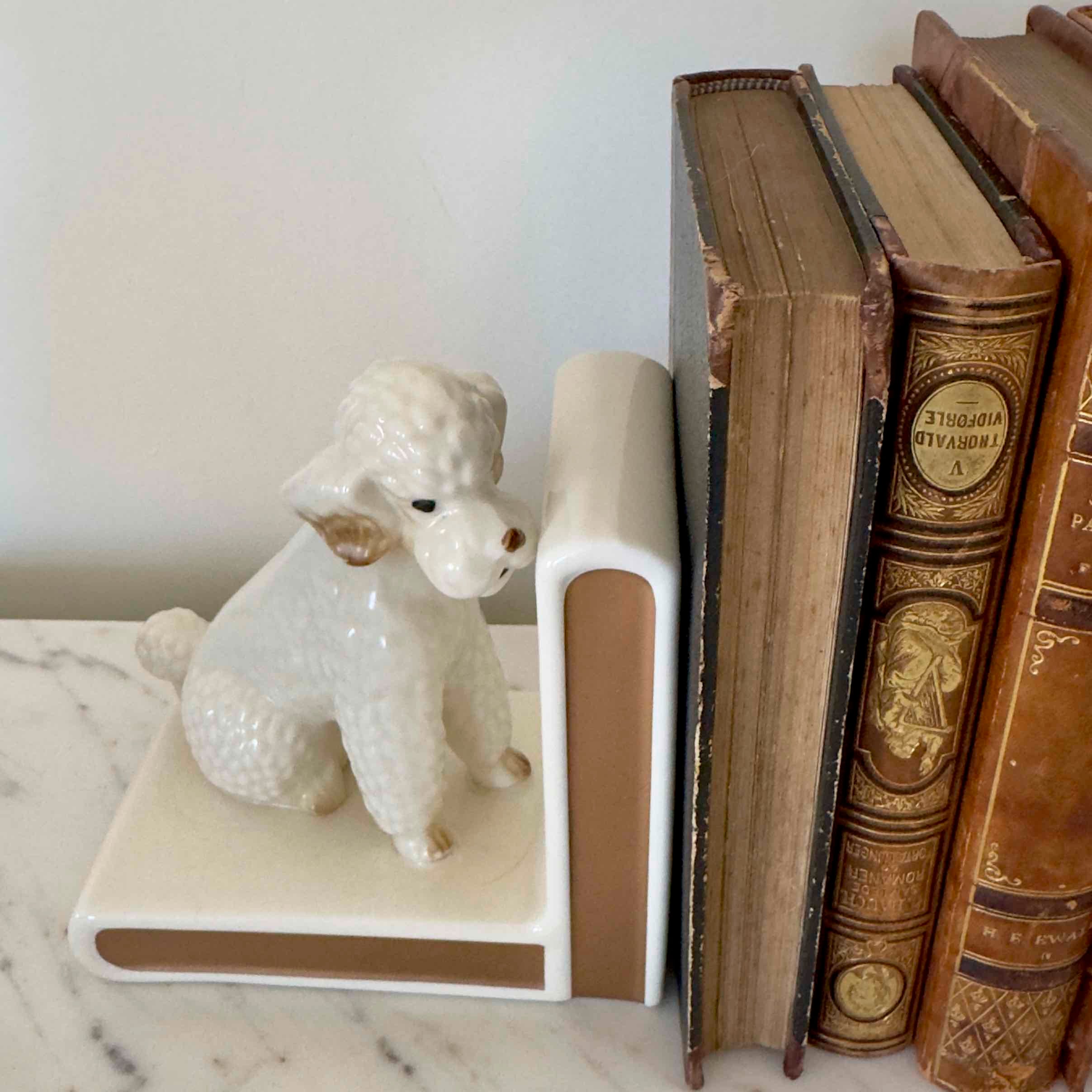 White ceramic poodle bookend on a stack of vintage books
