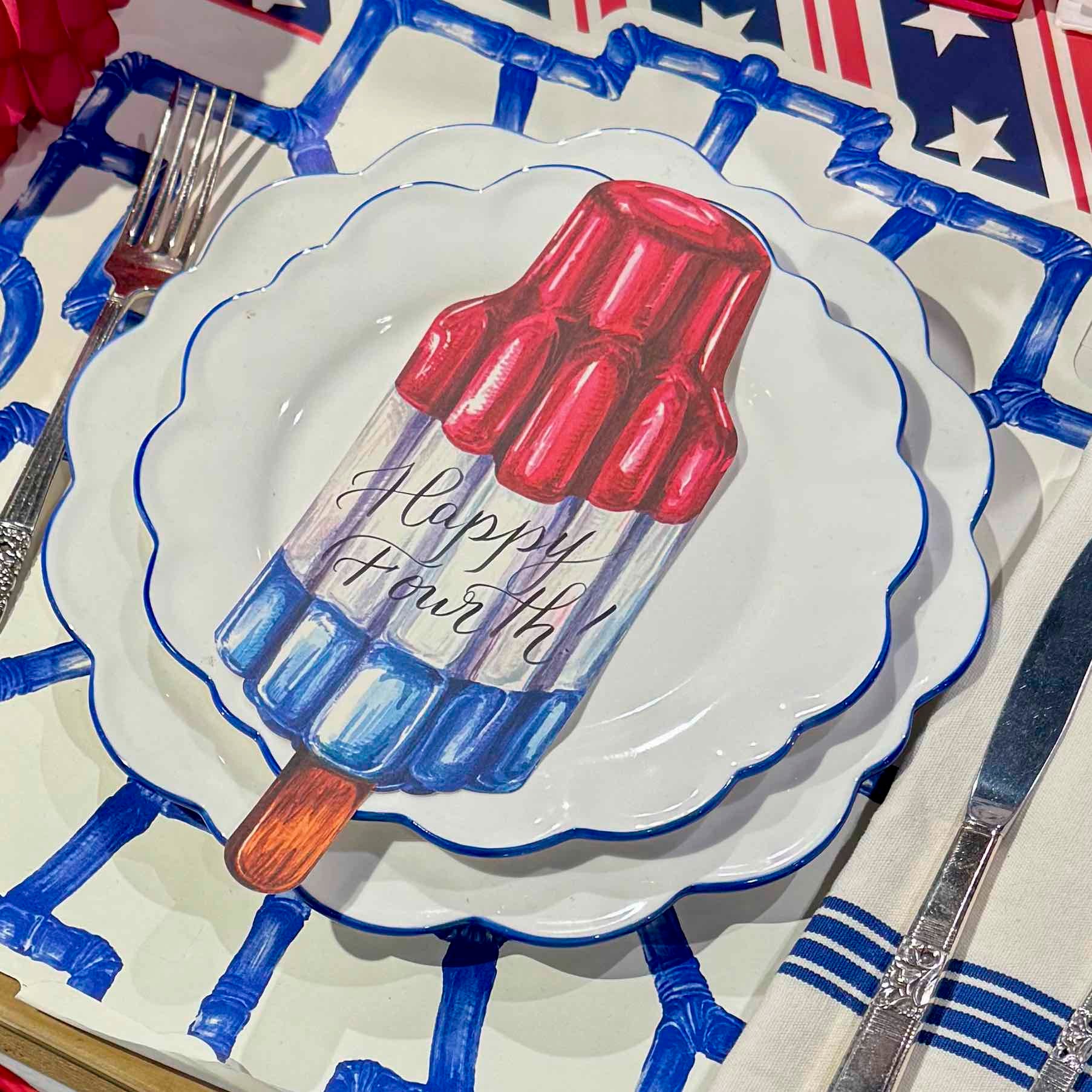 Decorative plate with a popsicle design and 'Happy Fourth' text on a table setting.