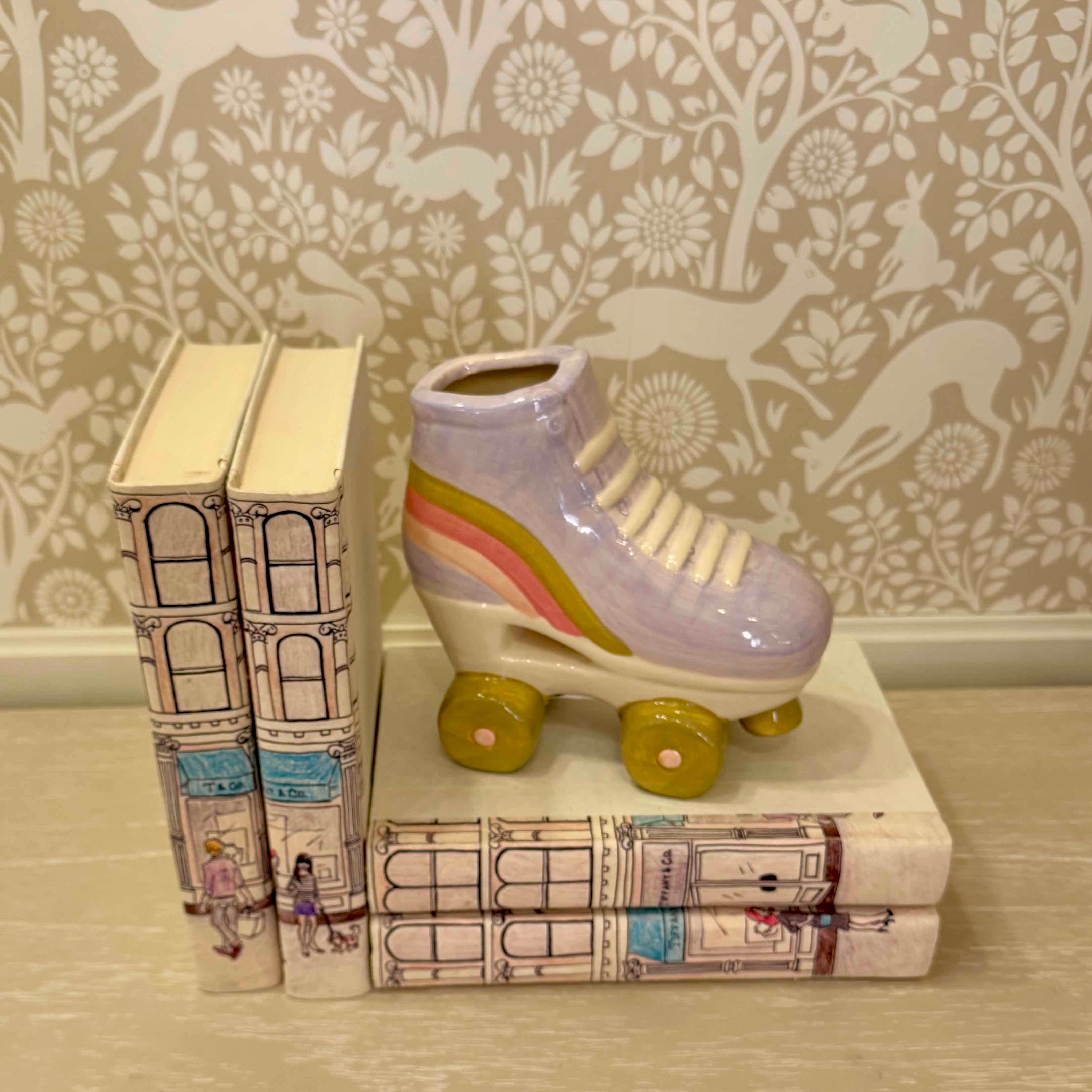 Ceramic roller skate on a stack of books with decorative wallpaper in the background