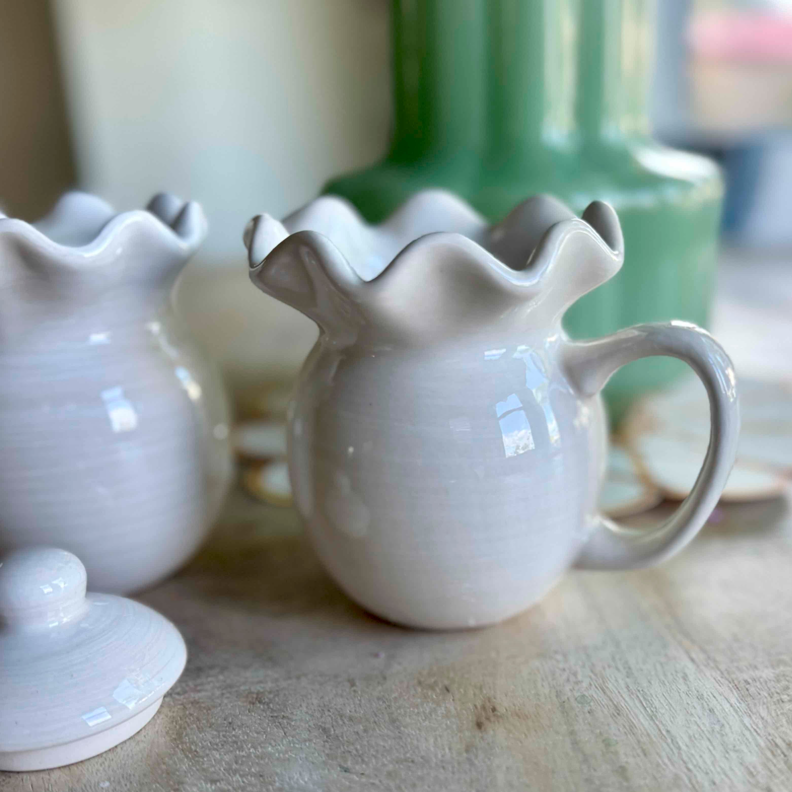 White ceramic pitcher with ruffled spout on a wooden surface