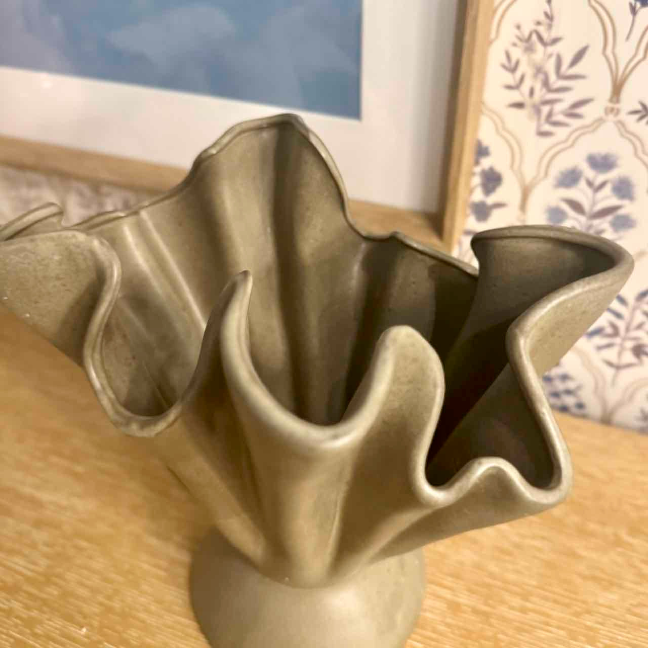 Decorative ceramic vase with wavy design on a wooden surface