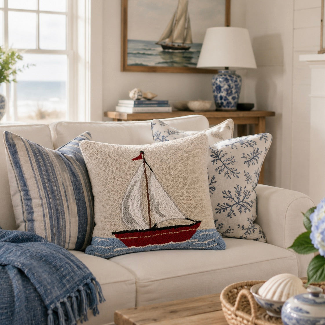 Cozy living room with a beige sofa featuring decorative pillows, a lamp, and a painting of a sailboat.