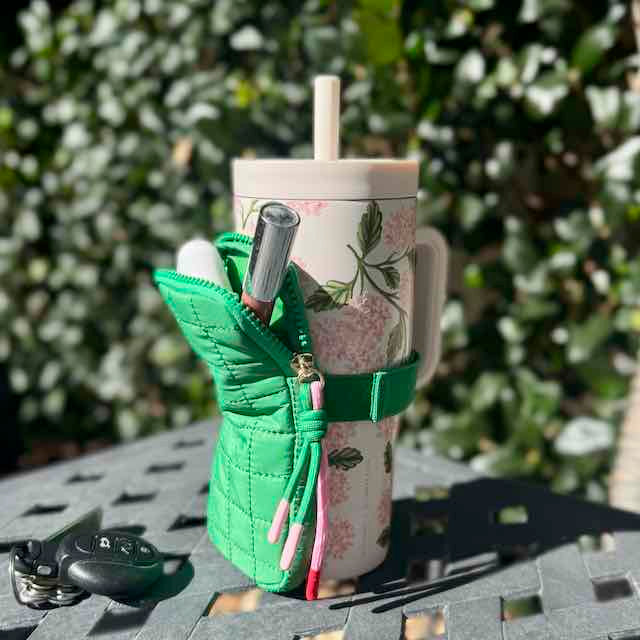 Green quilted pouch with a floral mug and straw on a table outdoors
