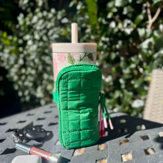 Green quilted mug holder with a floral mug on a table outdoors