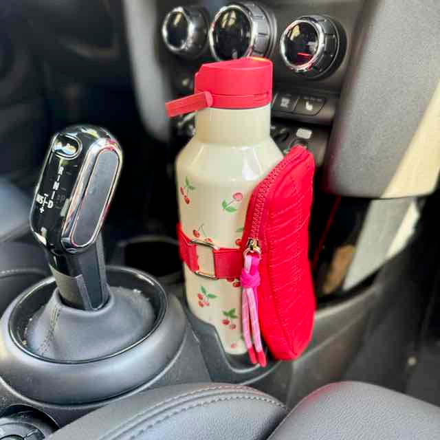 Water bottle with red lid and holder attached to a car's gear shift