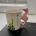 Ceramic mug with seahorse handle on a dark surface