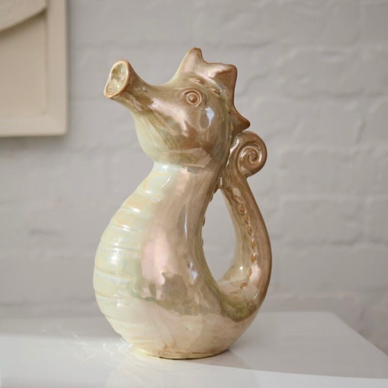Ceramic vase shaped like a seahorse on a plain background